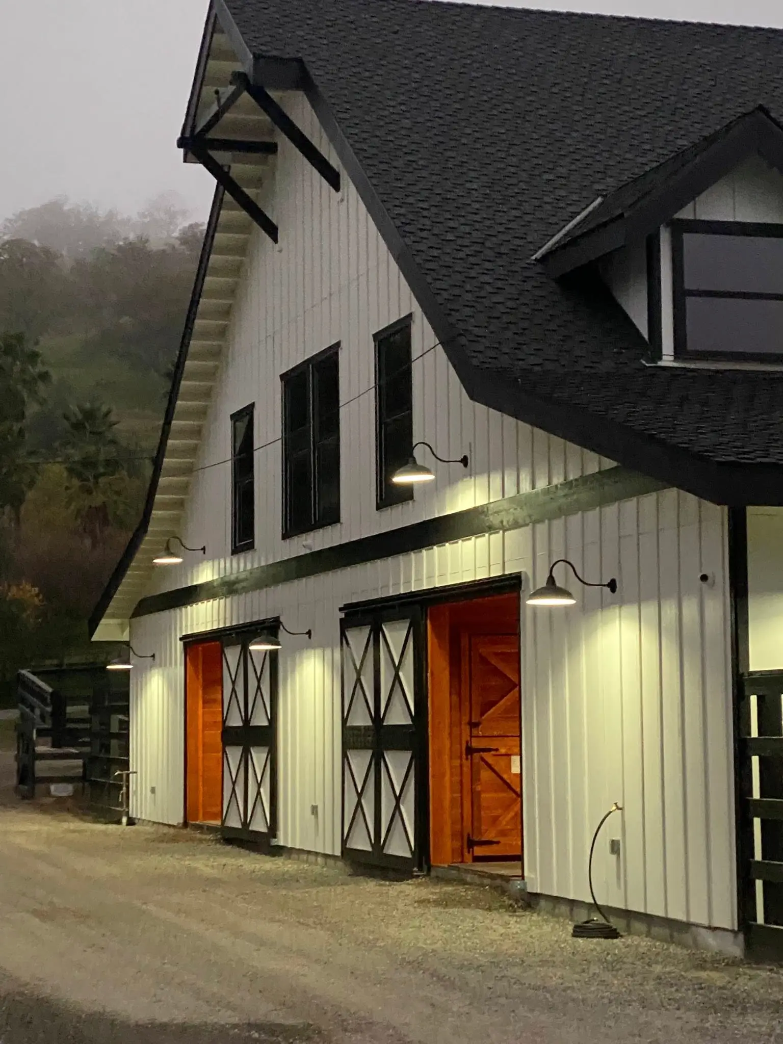 Close up of the stables at night of an equestrian center. The orange barn doors are well lit.